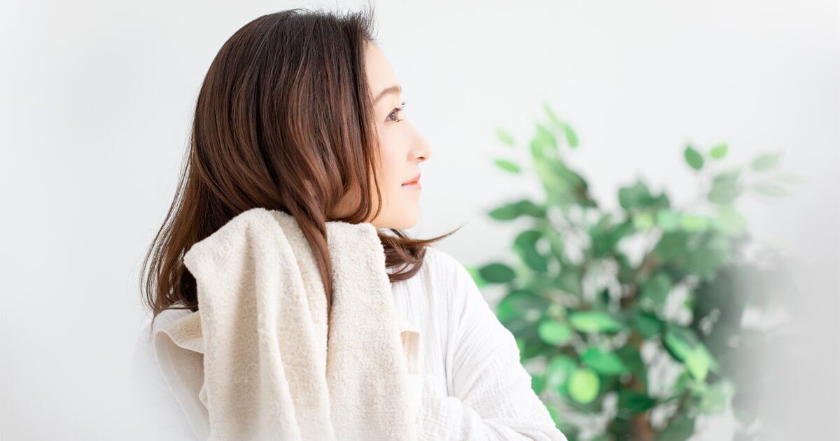 女性がタオルで髪の毛を乾かしている